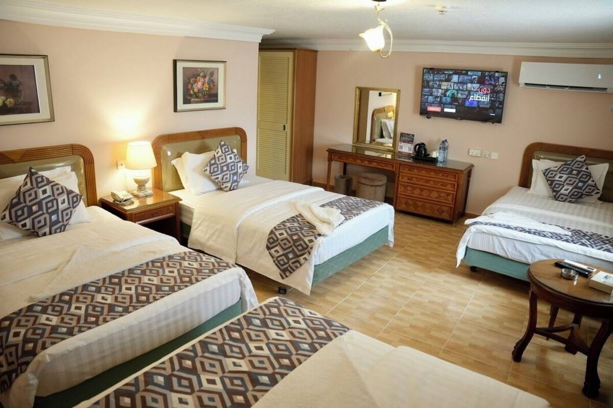 Ett hotellrum med två sängar, en byrå i trä, ett skrivbord och en tv.