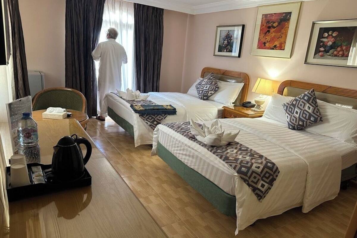 Ett hotellrum med två sängar, ett skrivbord med en kaffebryggare och en stol.
