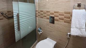 Un baño con ducha de vidrio, inodoro y barra para toallas.