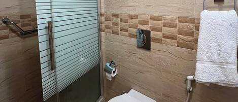 Un baño con ducha de vidrio, inodoro y barra para toallas.