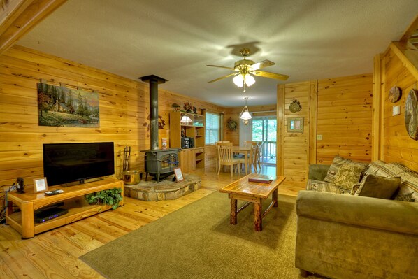 A cozy cabin interior with a wooden interior, a fireplace, a television, and a dining area.
