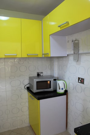 Compact kitchen with basic cooking facilities, including a microwave, kettle, and refrigerator.