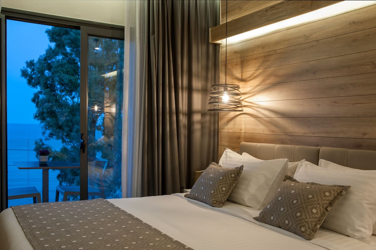 A bedroom with a large bed, a wooden headboard, and a view of the outdoors through a sliding door.