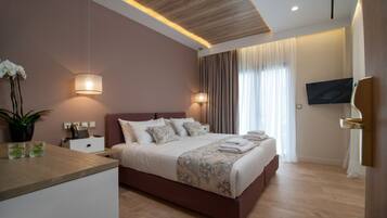 Un dormitorio moderno con techo de madera, una cama grande con ropa de cama floral, lámparas de noche, un televisor de pantalla plana y una planta en maceta.