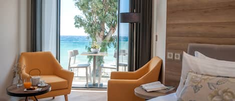 A hotel room with a bed, two armchairs, a small table with a drink and a book, and a view of the sea through a glass door.