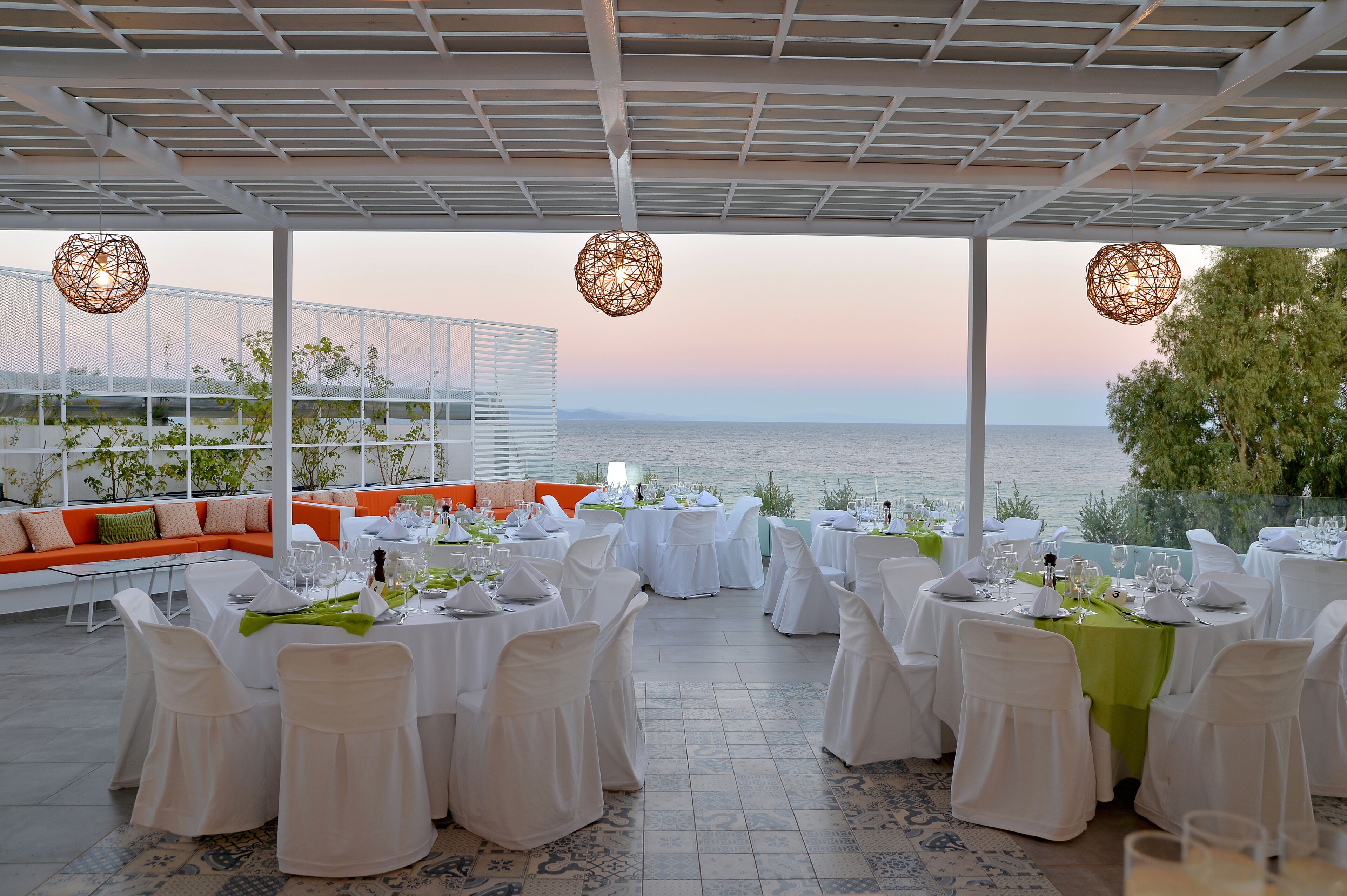 Un restaurant avec des tables rondes dressées pour le repas, donnant sur un plan d’eau.