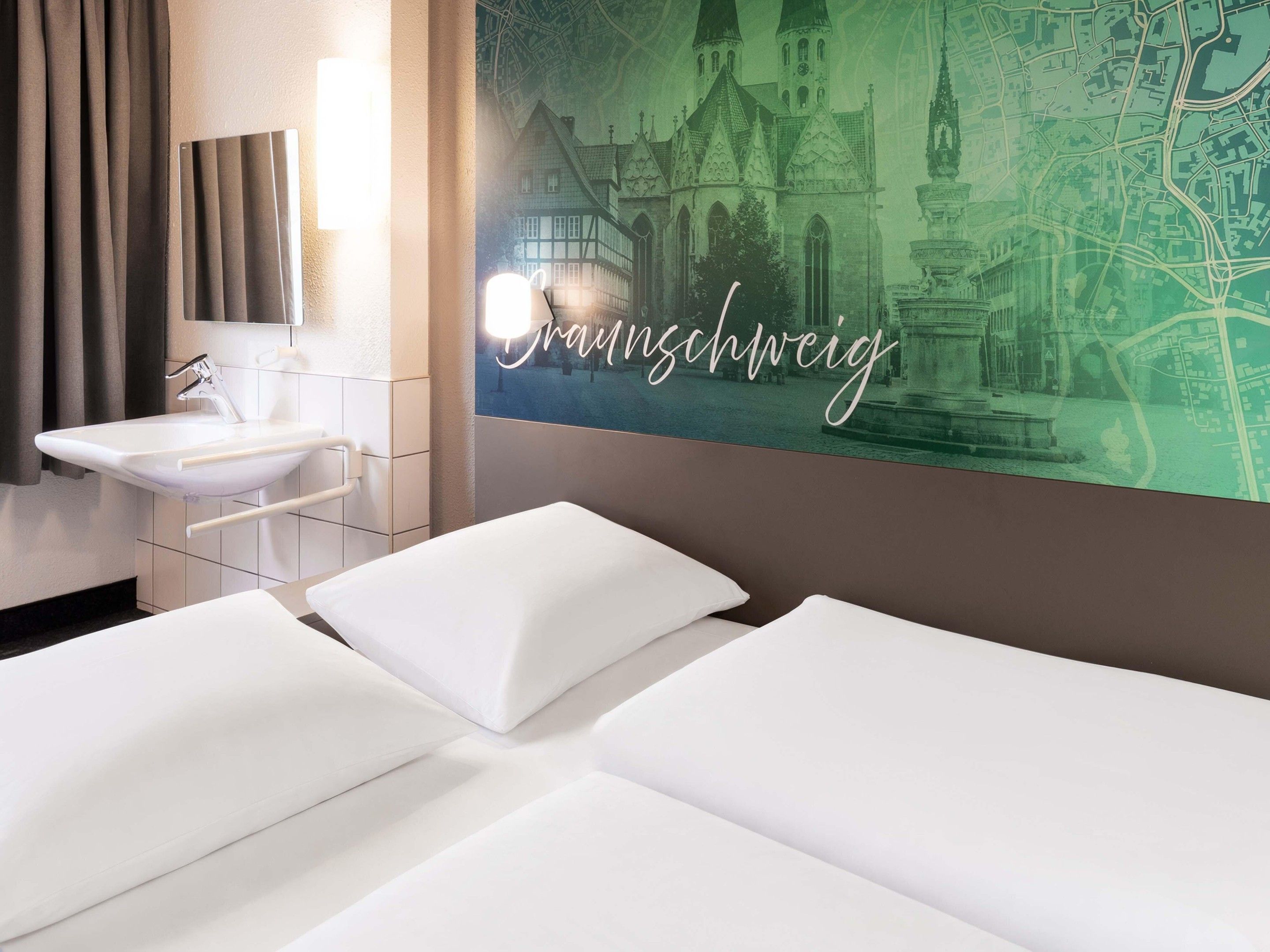 Ein Hotelzimmer mit einem Bett, einem weißen Waschbecken und einer Wand mit einem Stadtbild-Mural.