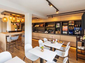 A modern cafe with a bar area, seating, and a variety of food and drink options.