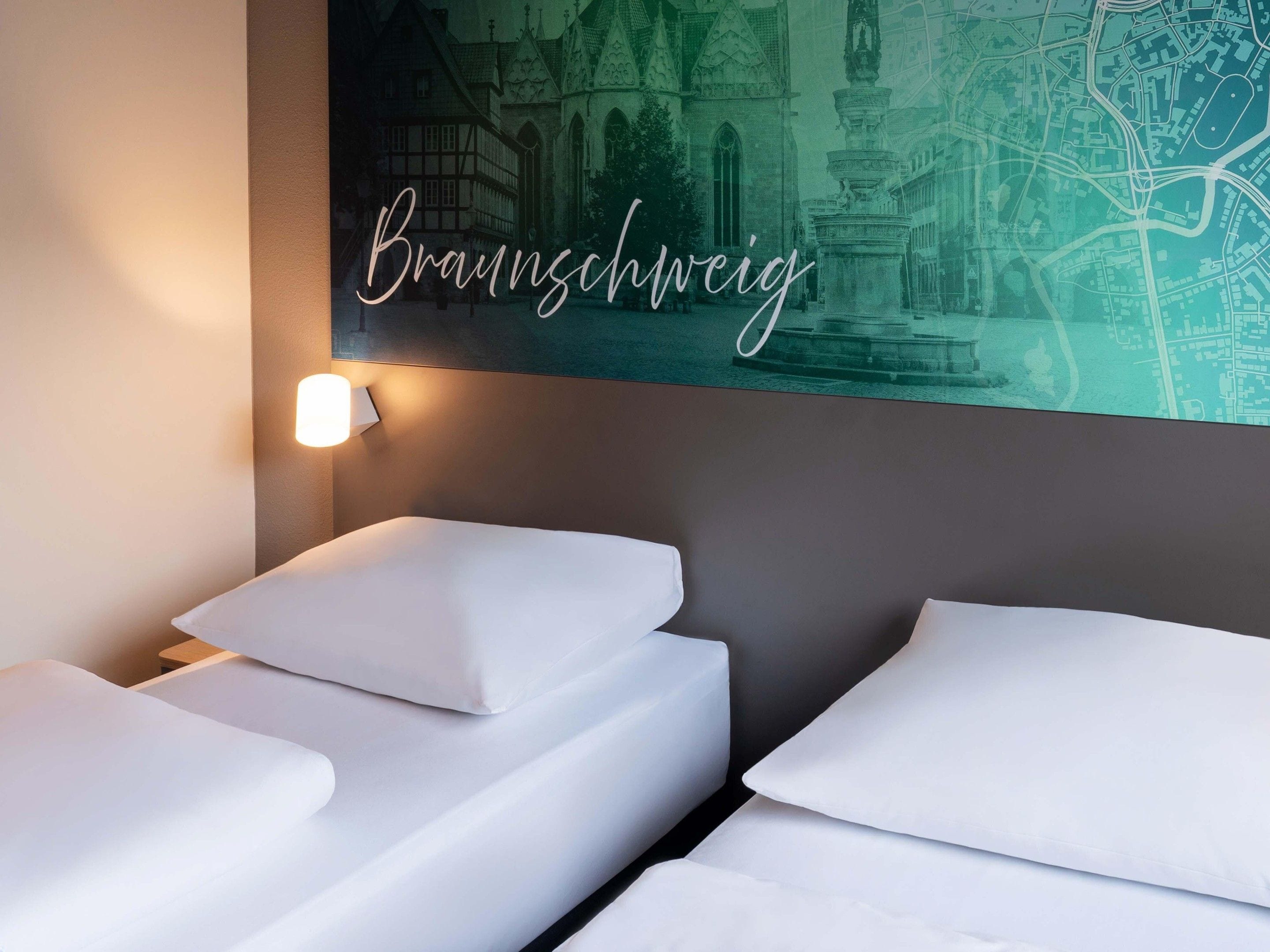 Ett hotellrum med två sängar, en karta som hänger på väggen och en vägglampa som är tänd.