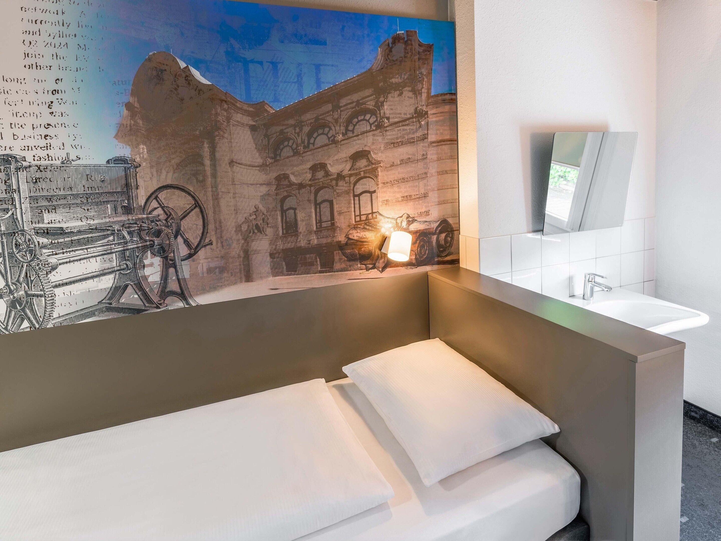 Un baño moderno con un espejo grande, un lavamanos y una lámpara en la pared.