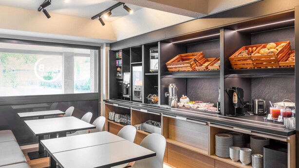 Una cafetería moderna con mesas, sillas y una barra con comida y bebidas.
