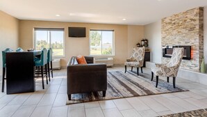 Una sala moderna con sofá, sillones, mesa de comedor y chimenea.