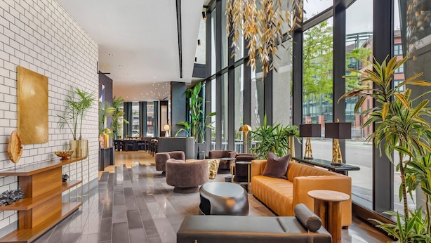 En modern entréhall med en receptionsdisk, sittgrupper och stora fönster med utsikt över staden.