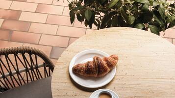 Una mesa de madera redonda con un plato de cruasanes y una taza de café.