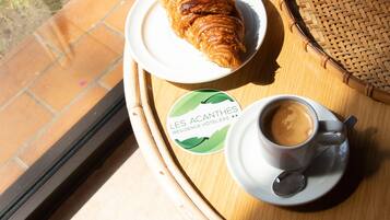 A table with a croissant, a cup of coffee, and a potted plant.