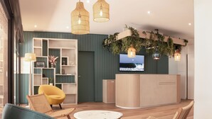 Una sala de estar moderna con un sofá, sillas, una mesa de centro y un televisor sobre un mueble de madera.