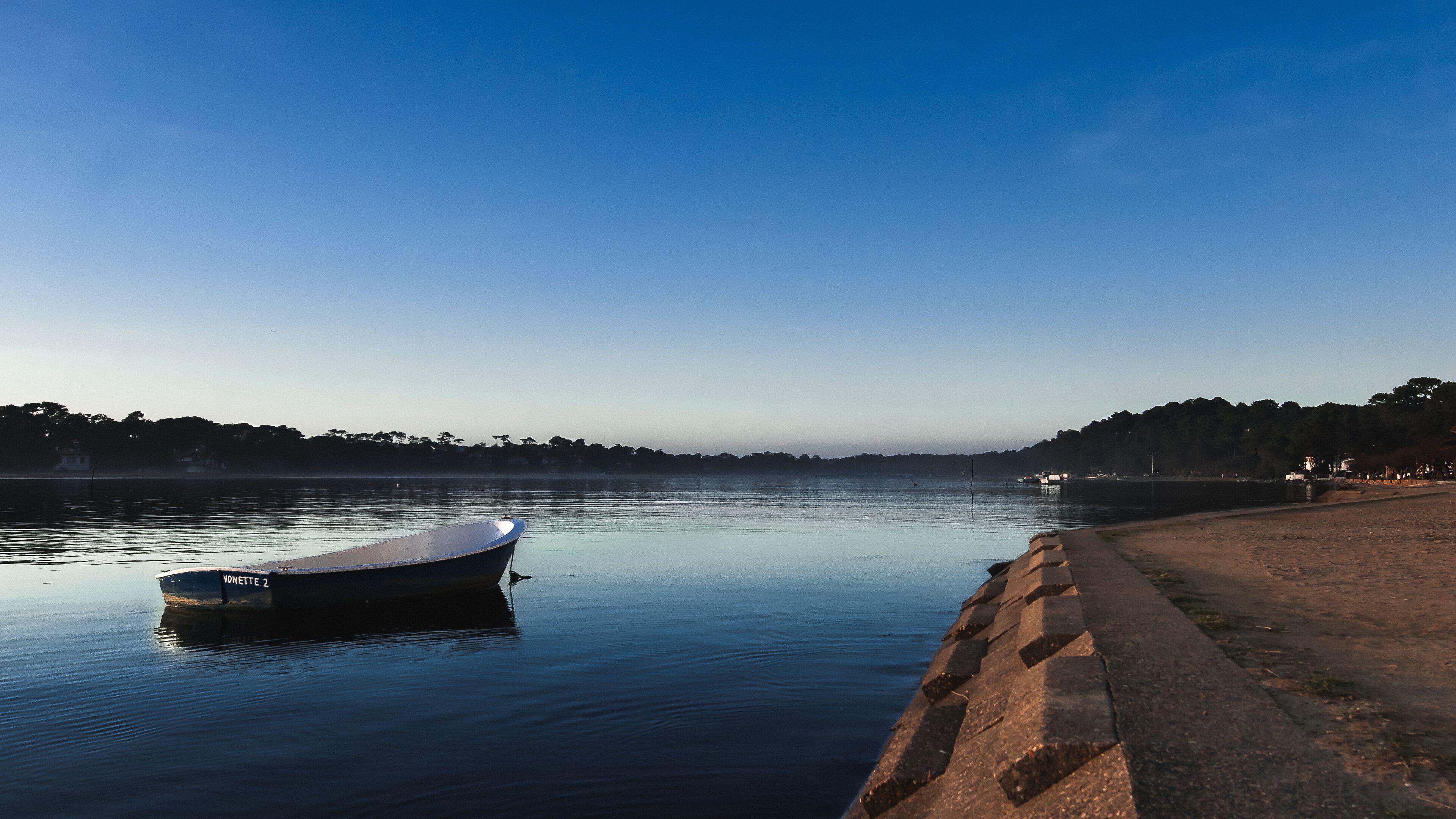 A calm river with a small boat docked on the left.