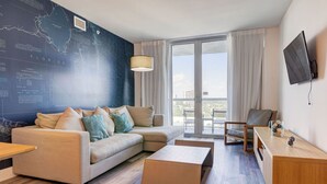Quarto de hotel moderno com uma janela grande, um sofá, uma mesa de centro, uma escrivaninha e um mapa na parede.