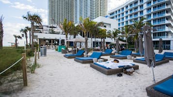 Perto da praia, espreguiçadeiras, guarda-sóis, toalhas de praia