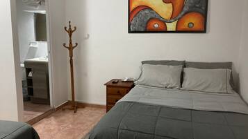 A bedroom with a bed, nightstand, and a painting on the wall.