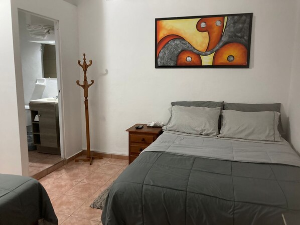 Un dormitorio con cama, mesita de noche y un cuadro en la pared.
