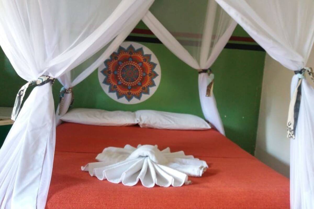 A bed with a red mattress, white pillows, and a white canopy.