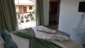 A bedroom with a bed, a TV, and a view of the outside. - Pousada Aconchego da Chapada (Alto Paraíso de Goiás)