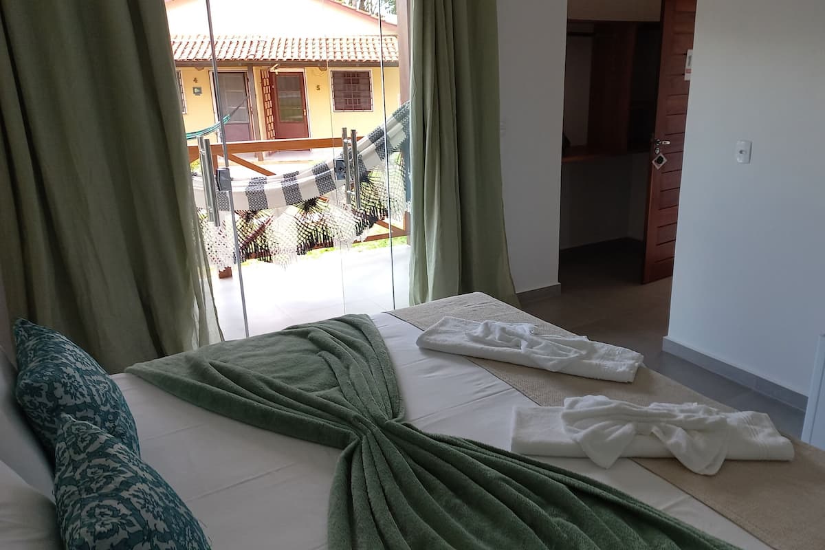 A bedroom with a bed, a TV, and a view of the outside.