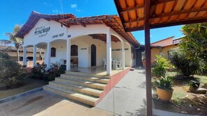 A building with a white facade, a tiled roof, and a covered entrance area with steps leading up to it. - Pousada Aconchego da Chapada (Alto Paraíso de Goiás)