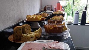A buffet with various food items including bread, pastries, and cheese. - Pousada Aconchego da Chapada (Alto Paraíso de Goiás)