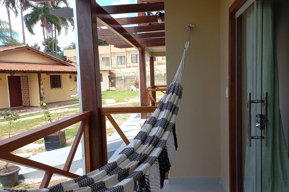 A hammock hanging on a balcony with a view of a building and palm trees.