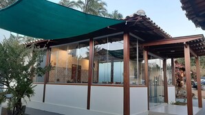 A modern building with large glass windows, a wooden pergola, and a green canopy. - Pousada Aconchego da Chapada (Alto Paraíso de Goiás)