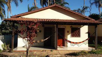 Uma casa térrea com telhado de telhas, porta da frente e pequena varanda.