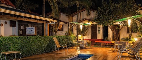 Un espace extérieur avec une piscine, des chaises longues et un coin salon abrité.