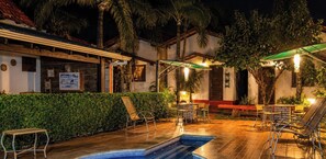 An outdoor swimming pool area with lounge chairs and a covered seating area. - Pousada Quinta Dos Quintais (Chapada dos Guimarães)