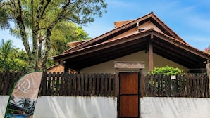 A small building with a wooden fence, a brown door, and a sign above the door. - Pousada Quinta Dos Quintais (Chapada dos Guimarães)