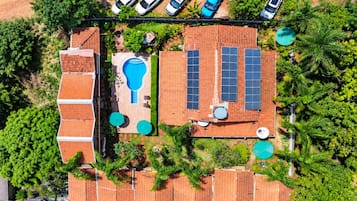 Vista aérea de una propiedad residencial con piscina, paneles solares y jardín cercado.