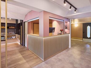 A reception area with a wooden counter, a computer, and a vase with flowers. -  B&B HOTEL Dortmund-Airport (Holzwickede)