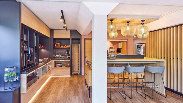 Una cocina moderna con barra, suelo de madera e iluminación colgante.