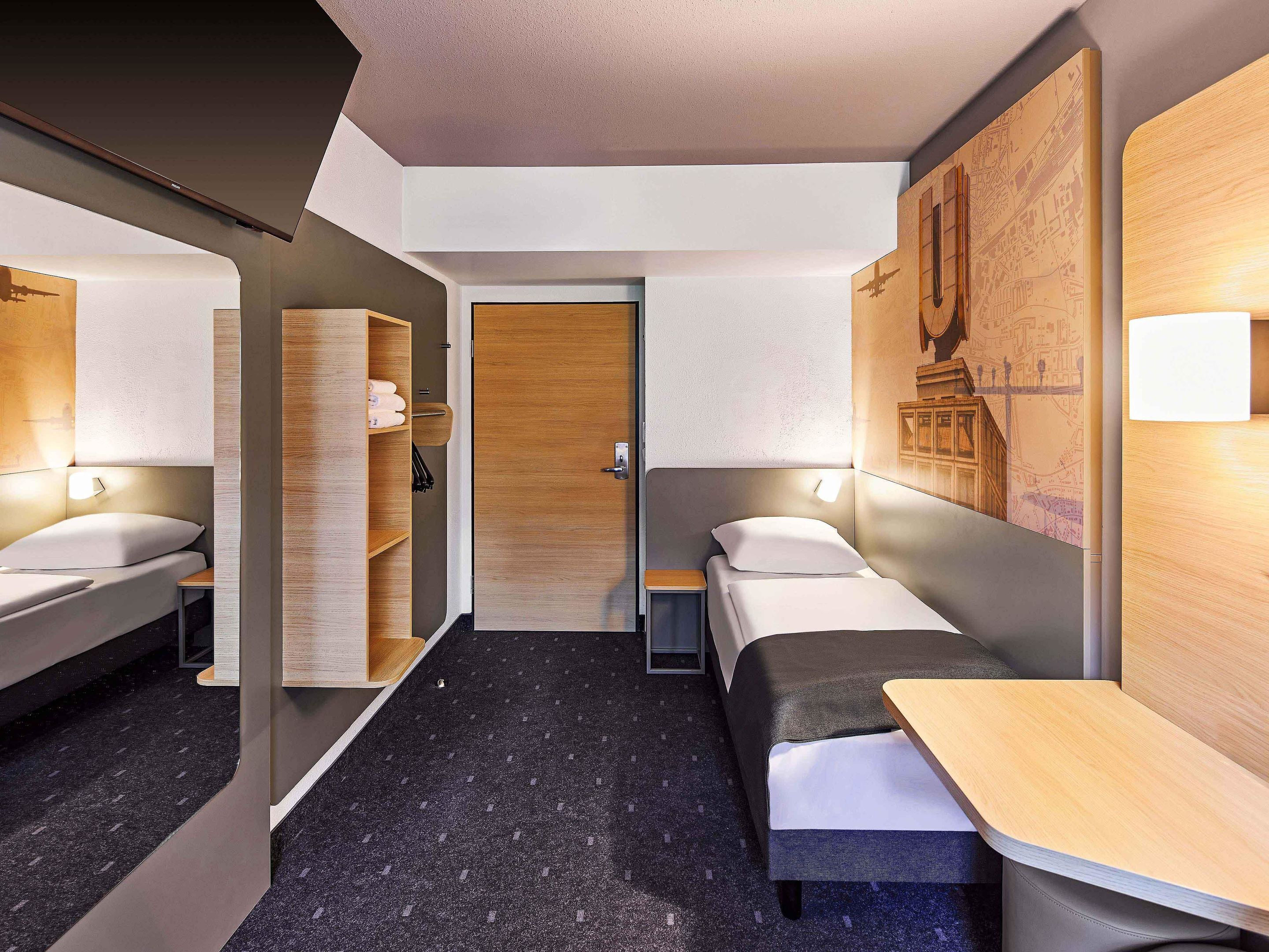 A modern hotel room with a bed, bedside tables, a wardrobe, and a map on the wall.