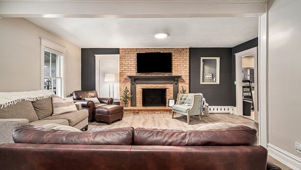Una sala de estar con chimenea, sofás de cuero, un televisor y una estantería.