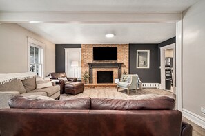A living room with a fireplace, leather sofas, a television, and a bookshelf. - The Gaylord Main House (Gaylord)