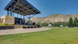 A building with a large open patio area, a stage, and a mountainous backdrop. - Walk to Beaver Creek Shuttle! Avon Condo w/ Deck (Avon)