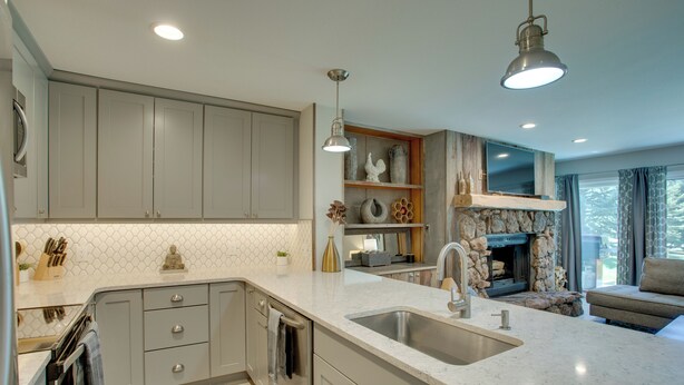A modern kitchen with a large island, built-in appliances, and a stone fireplace. - Walk to Beaver Creek Shuttle! Avon Condo w/ Deck (Avon)