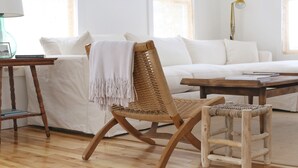 A modern living room with a white sofa, a wicker chair, a wooden coffee table, and a small side table with a lamp. - Downtown! Huge 3,000 sq. ft Historic CVX Cottage, Sleeps 16! New Central A/C!!! (Charlevoix)