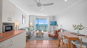 Une chambre d’hôtel moderne dotée d’un balcon, d’une télévision à écran plat, d’un coin repas et d’une kitchenette.