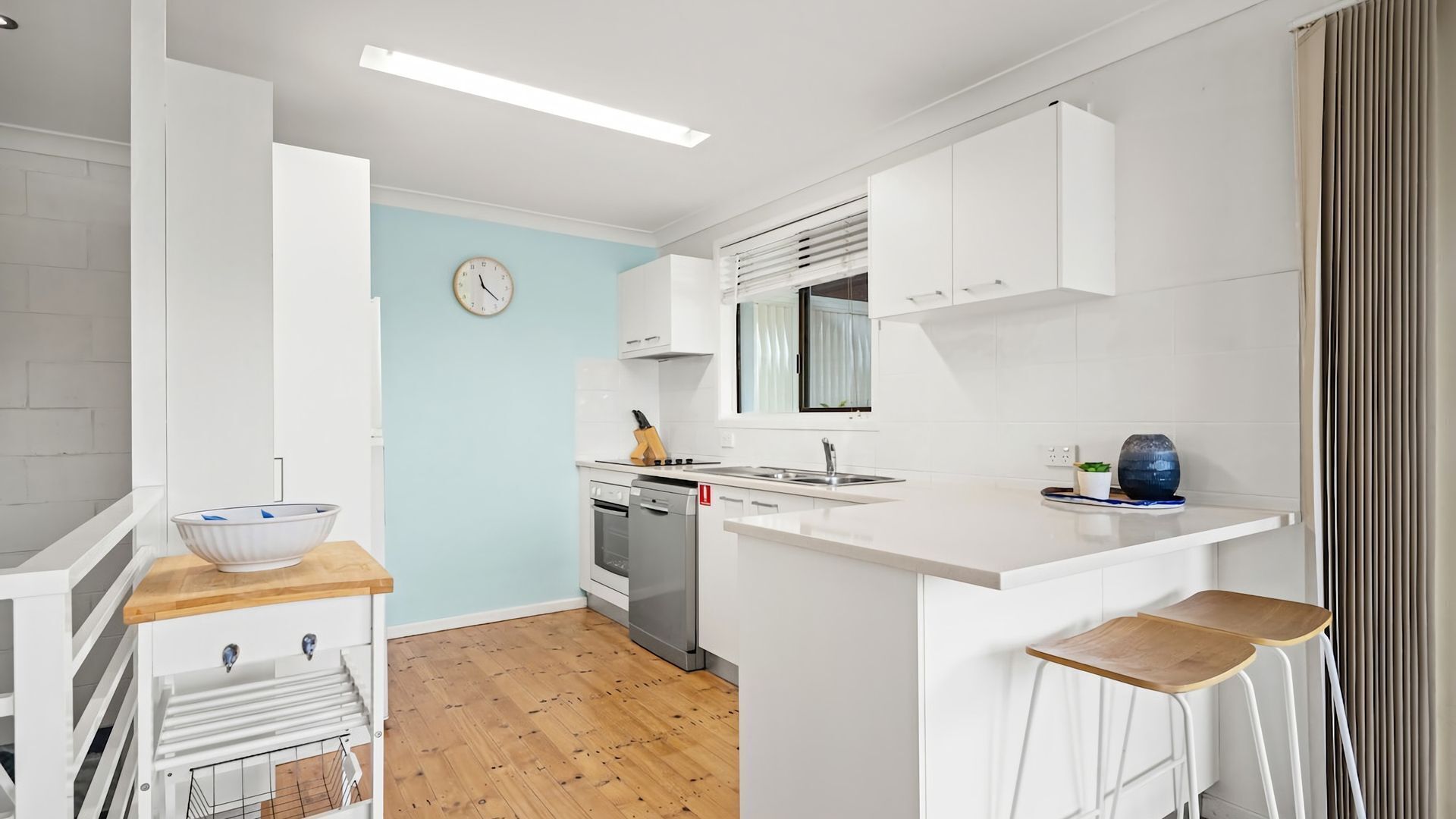 Una cocina moderna con armarios blancos, encimera de madera, un lavamanos y una estufa.