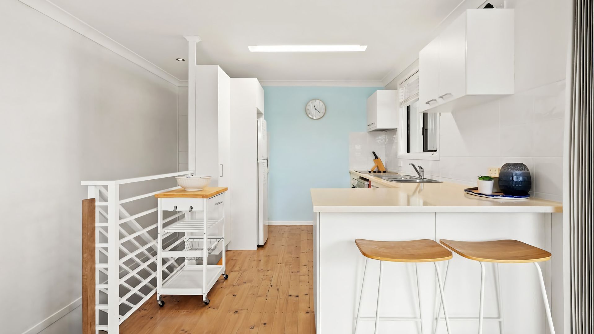 A modern kitchen with a central island, white cabinetry, and a light blue accent wall.