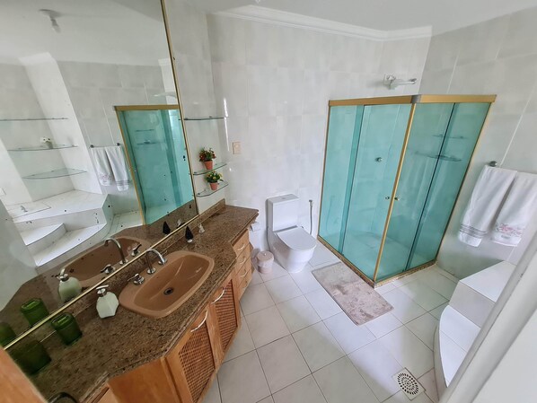 Une salle de bain moderne dotée d’une douche à parois de verre, d’un lavabo avec un plan de travail en granit et d’un miroir avec un cadre doré.