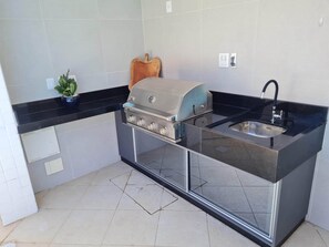 Enjoy cooking in this well-lit kitchen with a sleek countertop, stainless steel grill, and sink.